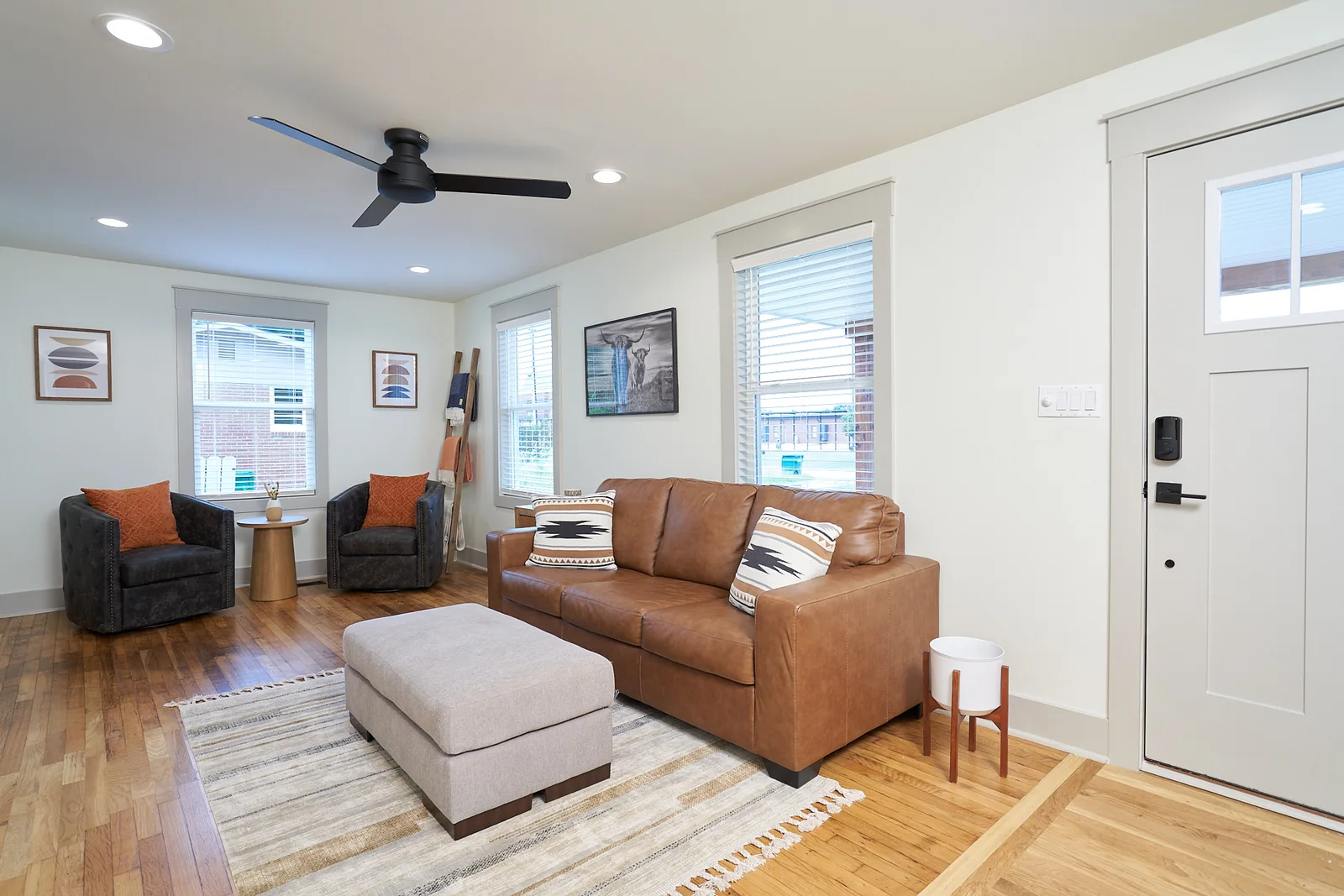 Bright living room with a leather sofa, armchairs, and original wood floors
