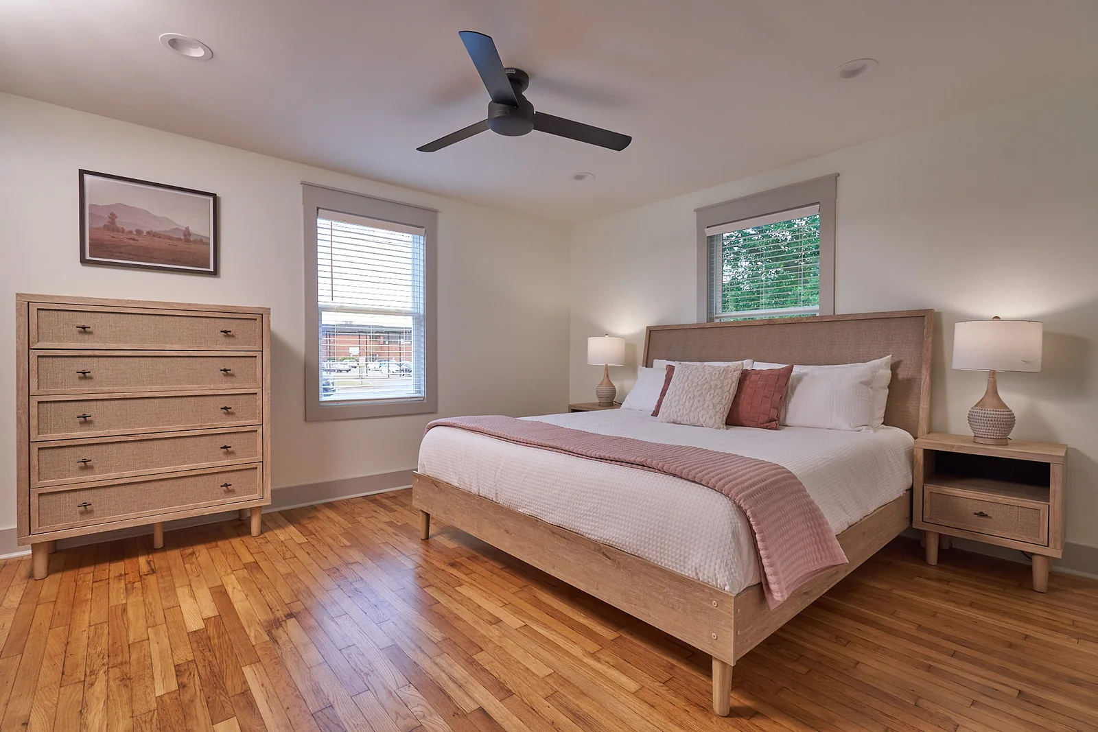 Second king bedroom with soft pink linens and hardwood floors